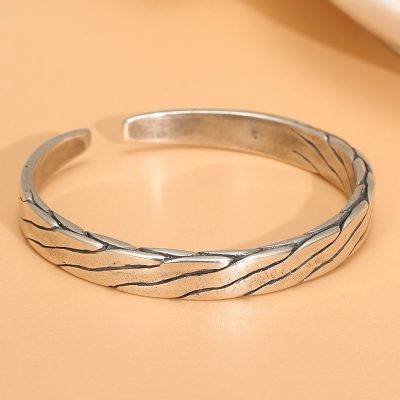 Sterling silver bangle bracelet with twisted open cuff, the entire bracelet is intricately carved with twisted patterns.