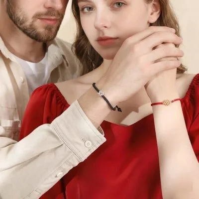 Couple holding hands wearing matching silver clover bracelets