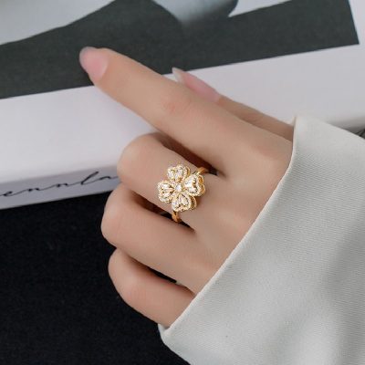 Elegant woman wearing a sterling silver spinner ring, a lucky flower fidget ring for anxiety relief. yellow gold color