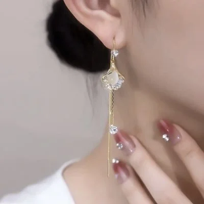 Elegant woman wearing long silver drop earrings with opal fan-shaped charms.