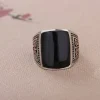Front angle view of a men's vintage sterling silver statement ring with a smooth flat square black agate stone and oxidized silver detailing