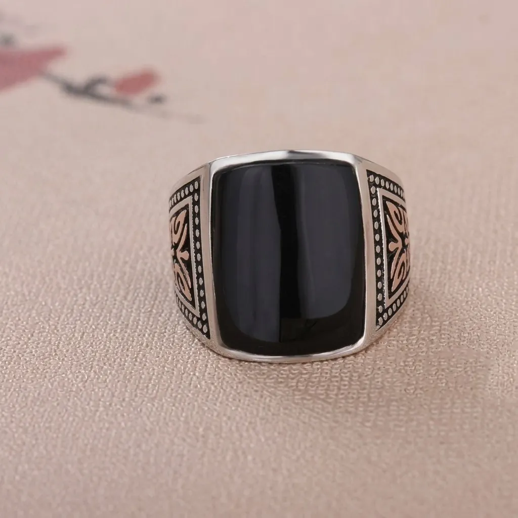 Front angle view of a men's vintage sterling silver statement ring with a smooth flat square black agate stone and oxidized silver detailing